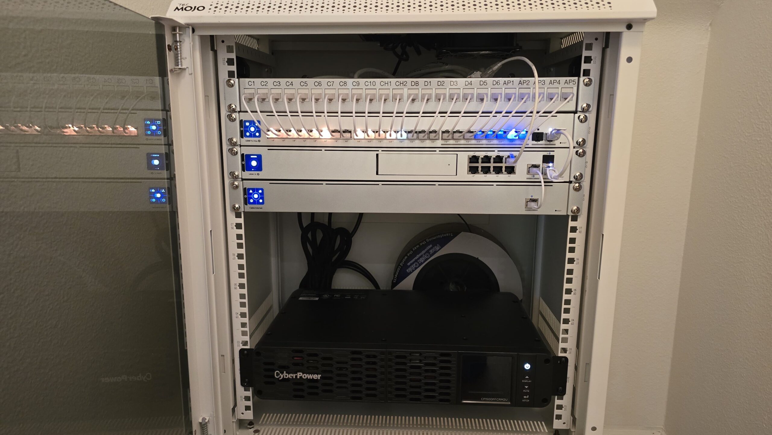 Installed network cabinet showing UniFi equipment, switches and neatly managed white patch cables
